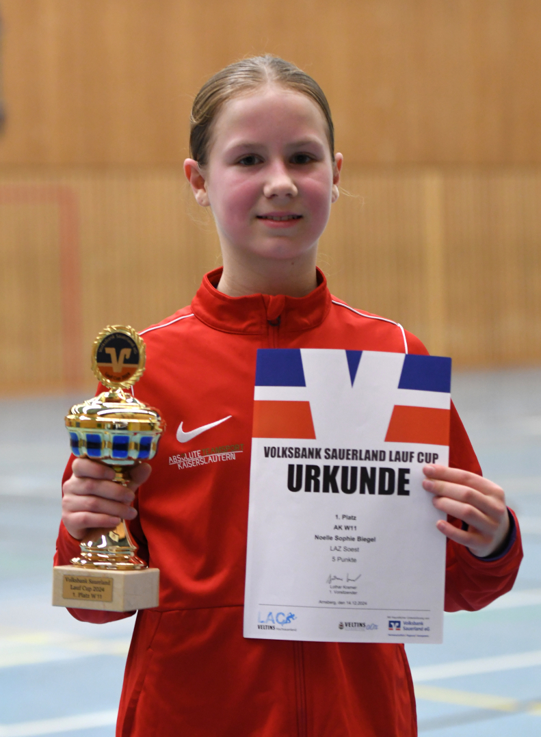 Pokal und Urkunde für den Gesamtsieg: W11-Sportlerin Noelle Biegel vom LAZ Soest entschied den Sauerland-Cup souverän für sich. Foto: Bottin|Sauerland-Cup-Siegerin Noelle Biegel (W11) vom LAZ Soest beim Silvesterlauf 2024 auf der Fünf-Kilometer-Strecke. Foto: Bottin|||