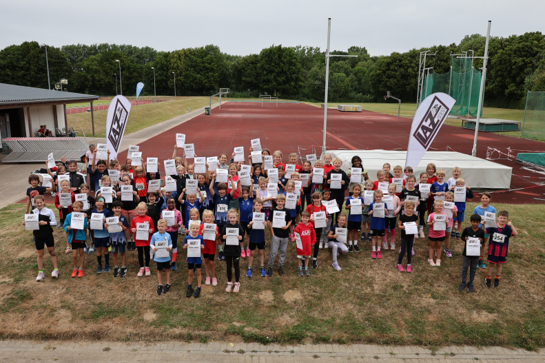 Freudestrahlende Teilnehmende nach einem erfolgreichen Wettkampftag|Romy aus dem U8-Team des LAZ Soest in Aktion bei der Hindernisstaffel. Foto: Bottin|U8-Kinder des USC Bochum beim Wechselvorgang in der Hindernisstaffel. Foto: Bottin|So gehts: Eine Dortmunder Trainerin zeigt ihren Schützlingen die richtige Haltung beim Absprung. Foto: Bottin|Außergewöhnlich: Eine perfekte Wurfauslage beim Schlagballwurf demonstriert hier Sophie Bornemann aus dem U12-Team des LAZ Soest. Foto: Bottin|Trainerin Maleen Klee mit drei U10-Mädchen des LAZ Soest beim Aufwärmen vor der Biathlonstaffel. Foto: Bottin|In der Strafrunde bei der Biathlonstaffel. Foto: Bottin|Beim Zielwerfen in den umgedrehten Sprungkasten hieß es: Treffen oder in die Strafrunde. Foto: Bottin|Beim Zielwerfen in den umgedrehten Sprungkasten hieß es: Treffen oder in die Strafrunde. Foto: Bottin|Zahlreiche Eltern waren zur Unterstützung ihrer Kinder im Soester Schulzentrum vor Ort. Foto: Bottin|Kurvenlage: Lucia Heitmann vom LAZ Soest in der Strafrunde bei der Biathlonstaffel. Foto: Bottin|Trainerin Maya Klute mit Kindern des U8-Teams des LAZ Soest vor der Biathlonstaffel. Foto: Bottin|Warten auf die Siegerehrung. Foto: Bottin|Das Team der Bielefelder Turngemeinde siegte bei den U10-Kindern. Foto: Bottin|Das Team der Bielefelder Turngemeinde siegte bei den U10-Kindern. Foto: Bottin|Platz zwei: Das U12-Team des LAZ Soest mit den Trainern Jana Klee und Levi Klute. Foto: Bottin|Platz vier für die Jüngsten: Die U8-Kinder von LAZ-Trainerin Christiane Noll. Foto: Bottin|||